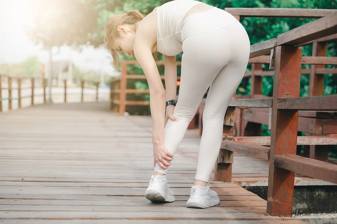 Woman experiencing Achilles tendon pain during exercise