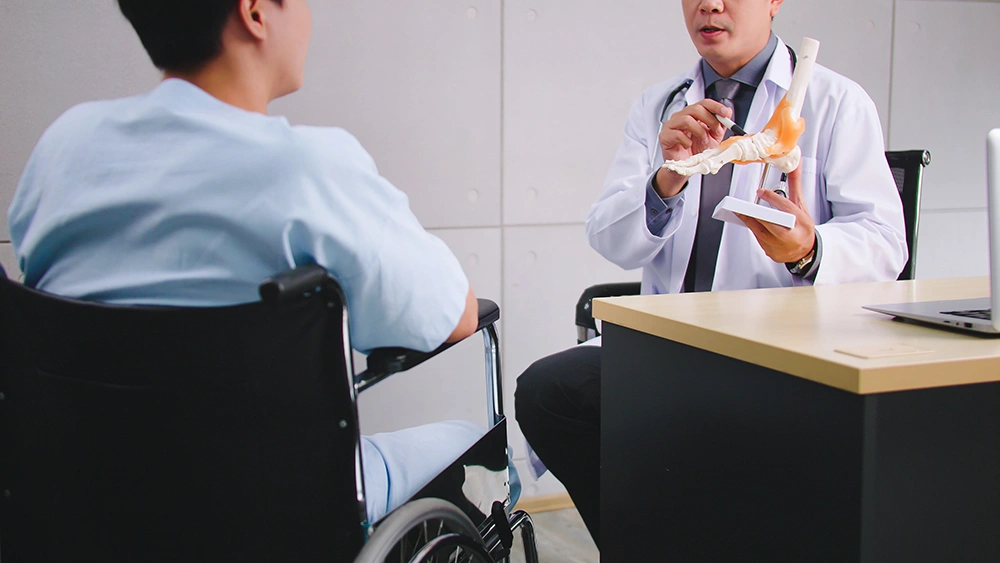 Doctor explaining ankle joint condition to patient during ankle replacement consultation.