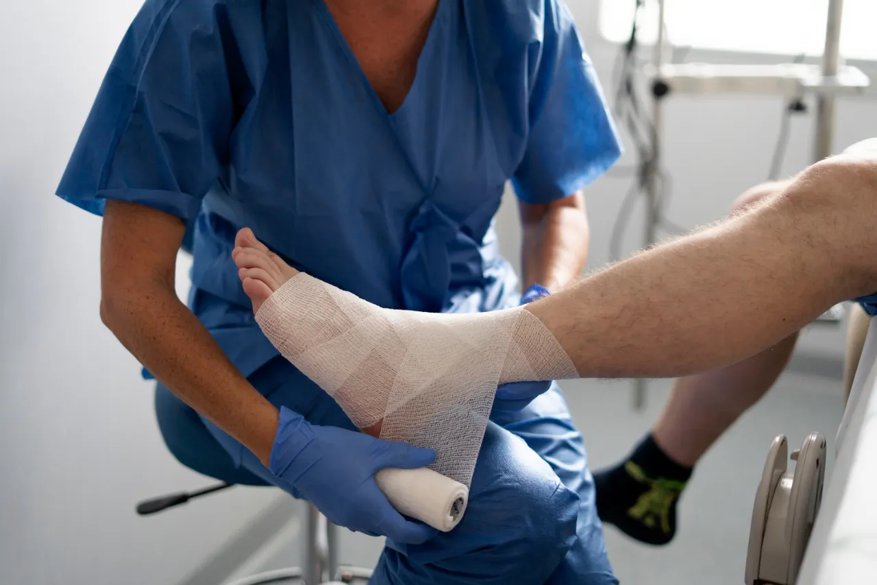 Medical professional applying bandage to patient's sprained ankle