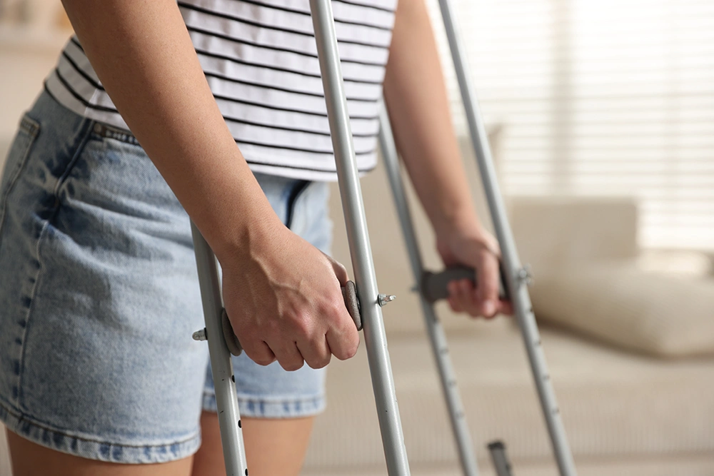 Woman using crutches at home while recovering from bunion surgery. 