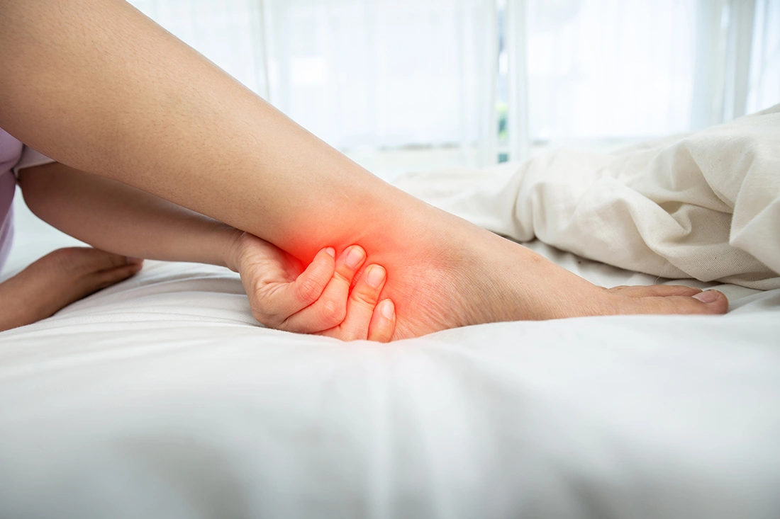 A woman’s feet showing signs of ankle pain while she rests in bed