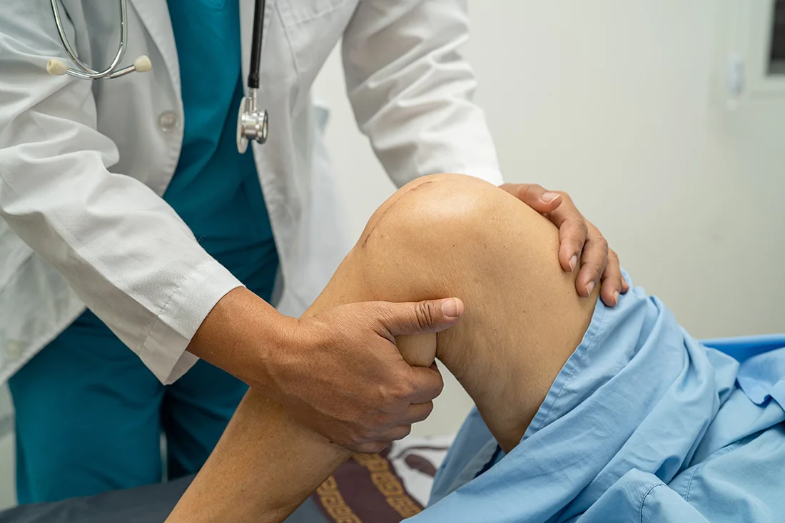 Doctor examining a patient’s knee during a consultation