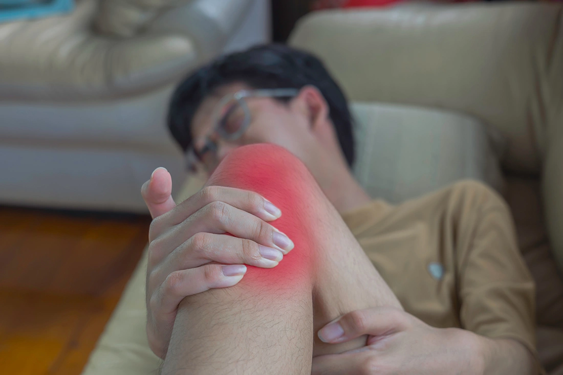 A man experiencing knee pain while resting